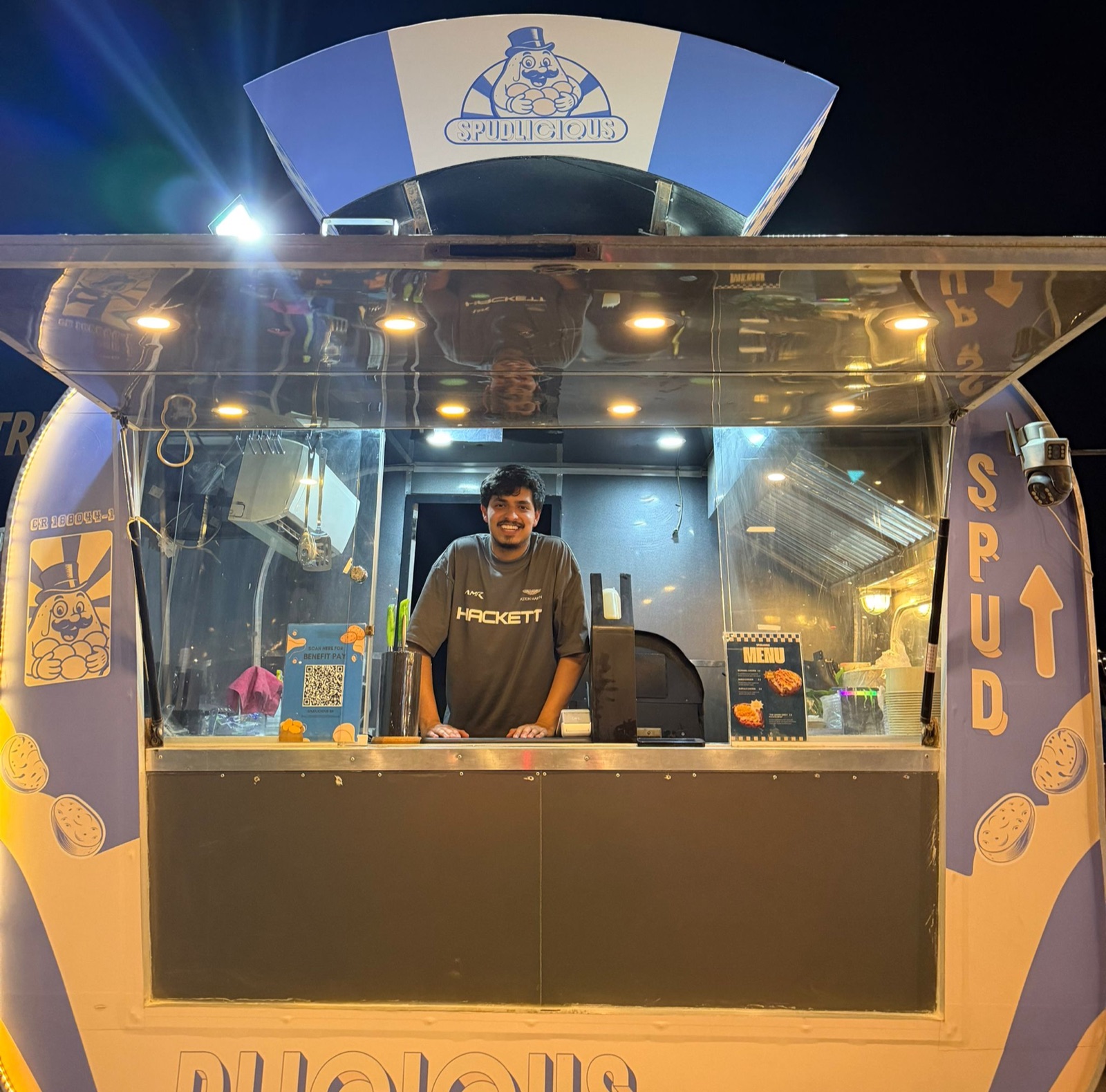 Abdulrahman Alhamad, founder of Spudlicious, standing at his food truck window in Busaiteen at night