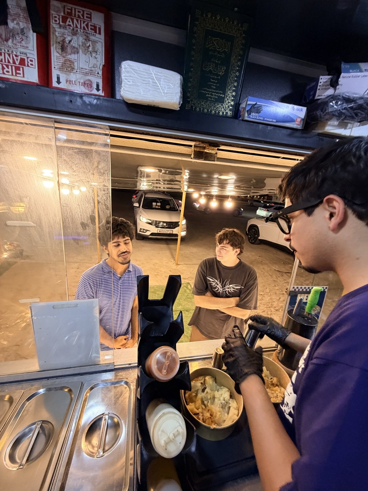 Customers ordering at the Spudlicious truck window at night