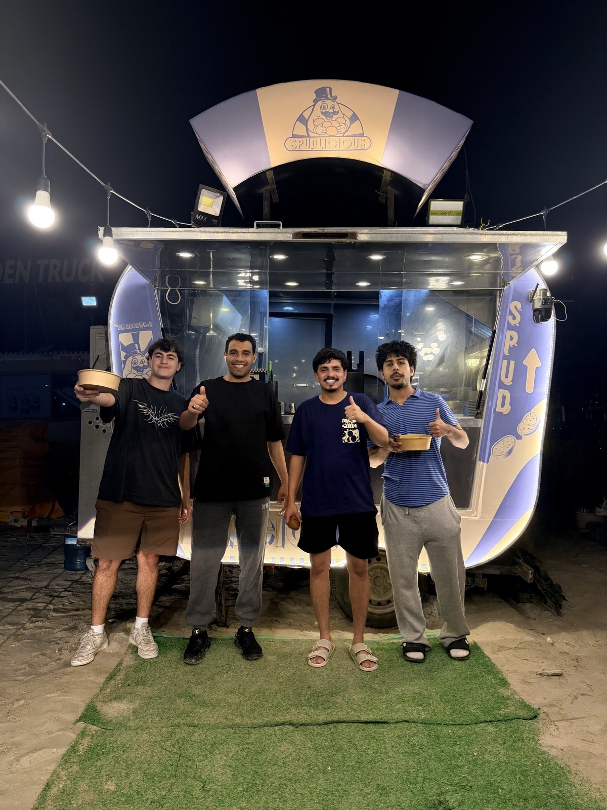 The Spudlicious team and friends gathered at the truck at night