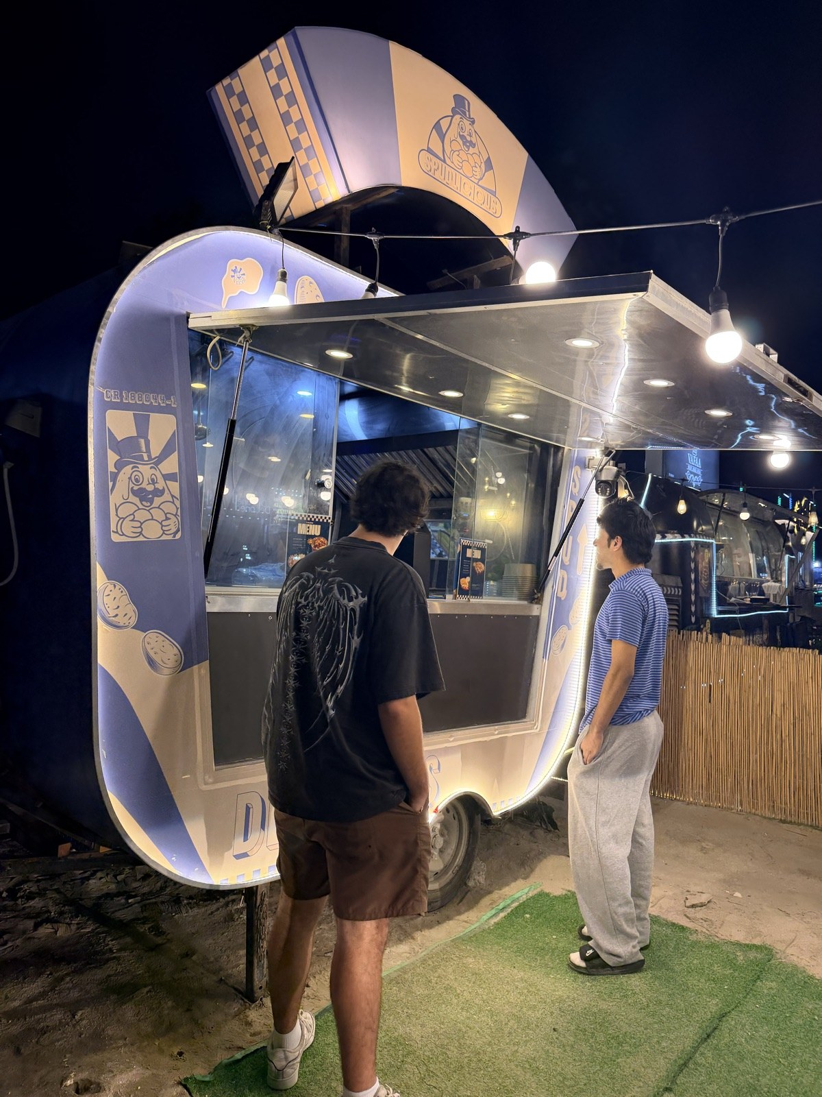 The glowing Spudlicious truck at night with customers